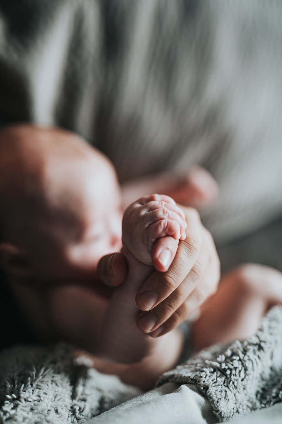 A newborn baby's hand held in an adult's